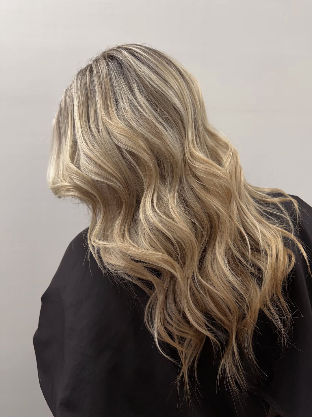 Back view of long blonde balayage with a soft, darker root and relaxed waves