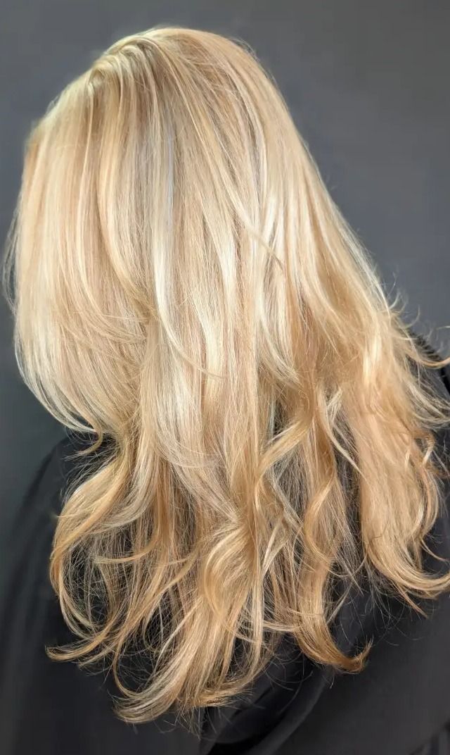 Back view of luminous golden blonde hair in relaxed waves against a dark background