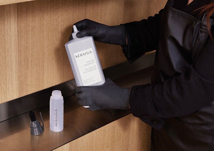 Kerasilk brand photo: a gloved hand holds the Keratin Treatment bottle beside an applicator, ready to be filled