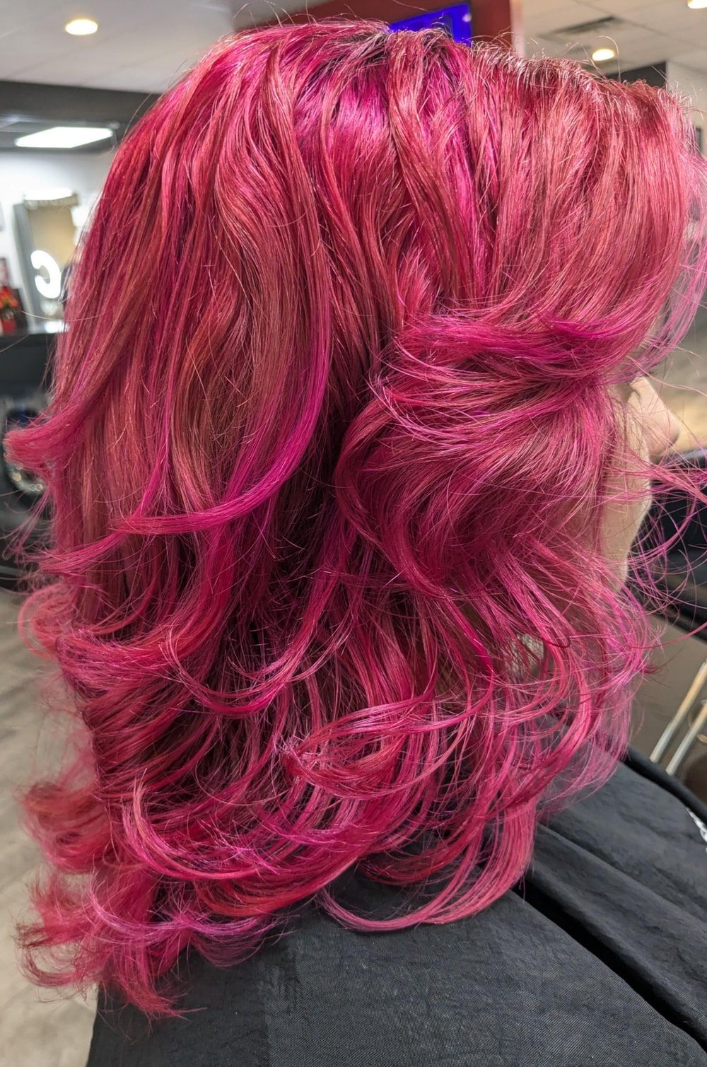 Real client with vivid magenta hair finished in loose, bouncy curls