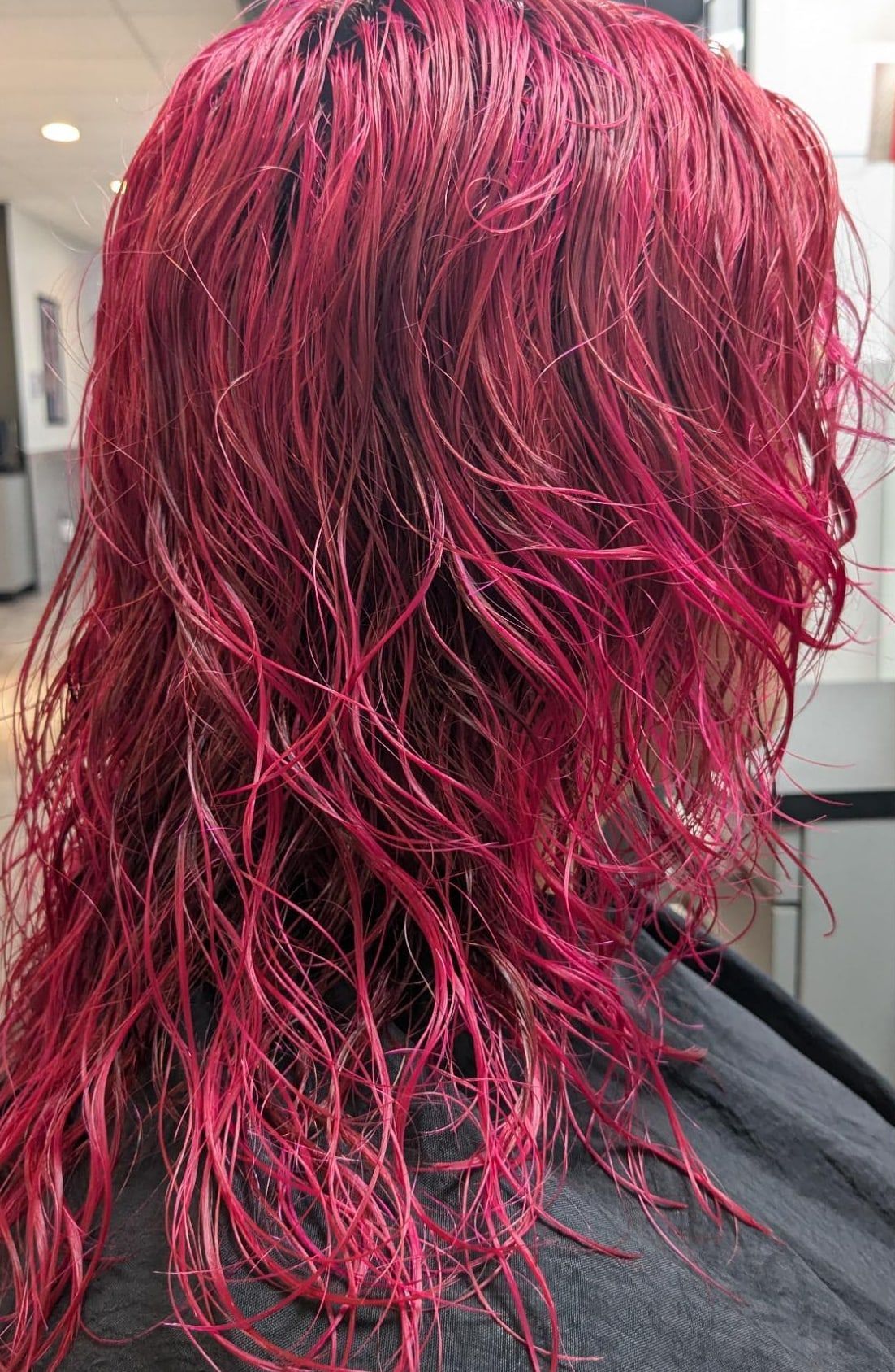 Freshly applied magenta on wet hair, photographed from behind in the salon
